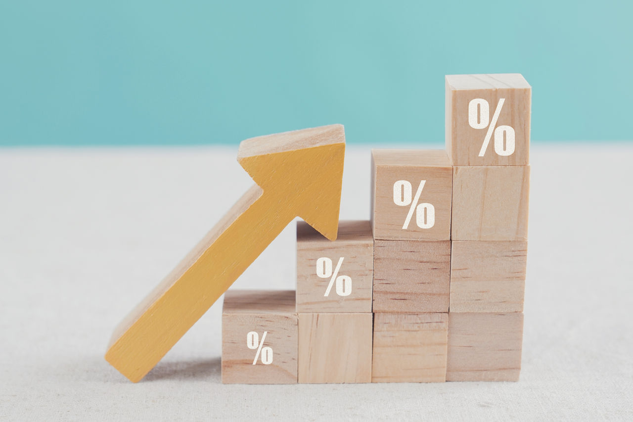 Wooden blocks with percentage sign and arrow up, financial growth, interest rate increase, inflation, high price and tax rise concept 